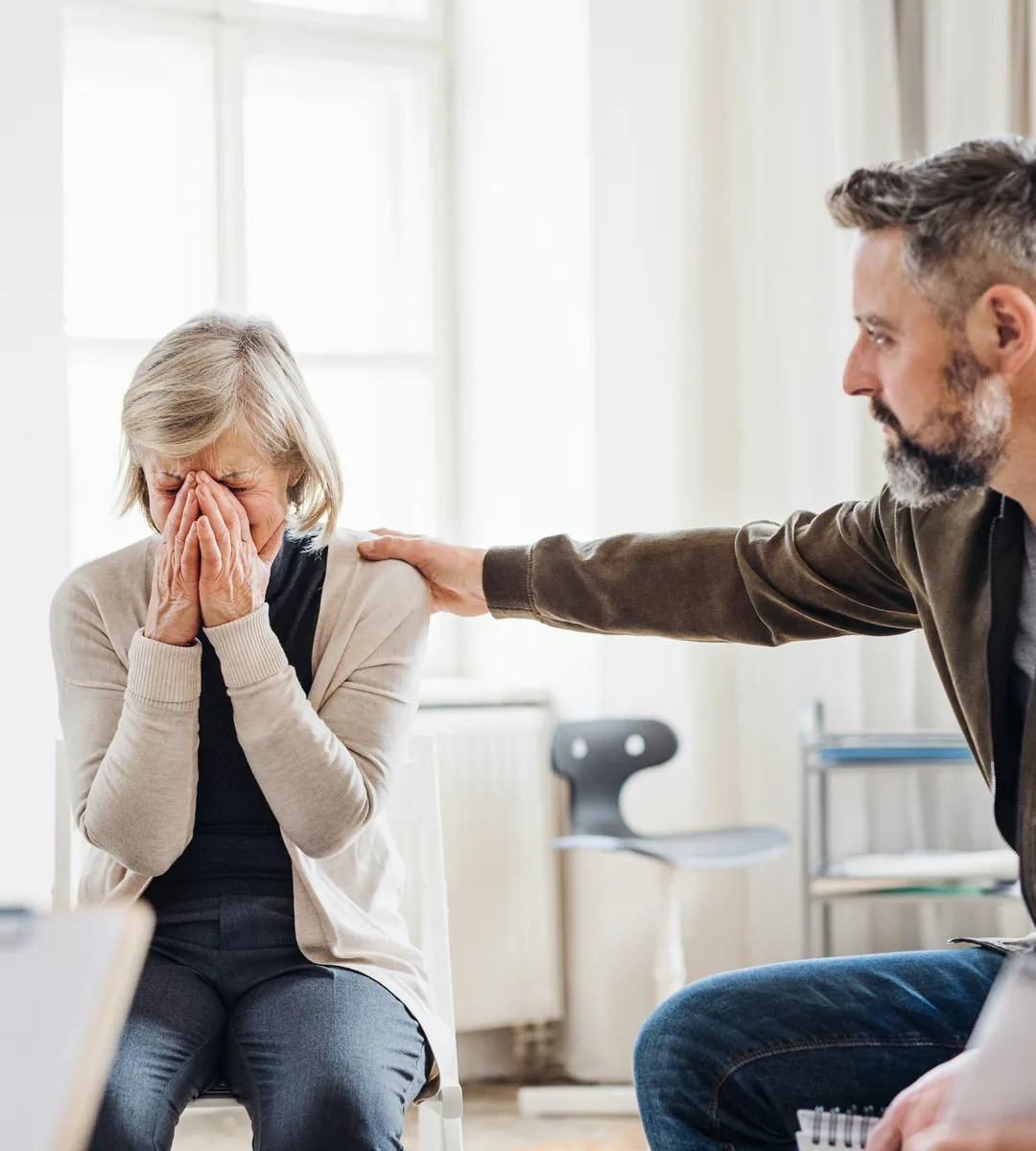 A grieving woman being comforted by a man with his hand on her shoulder
