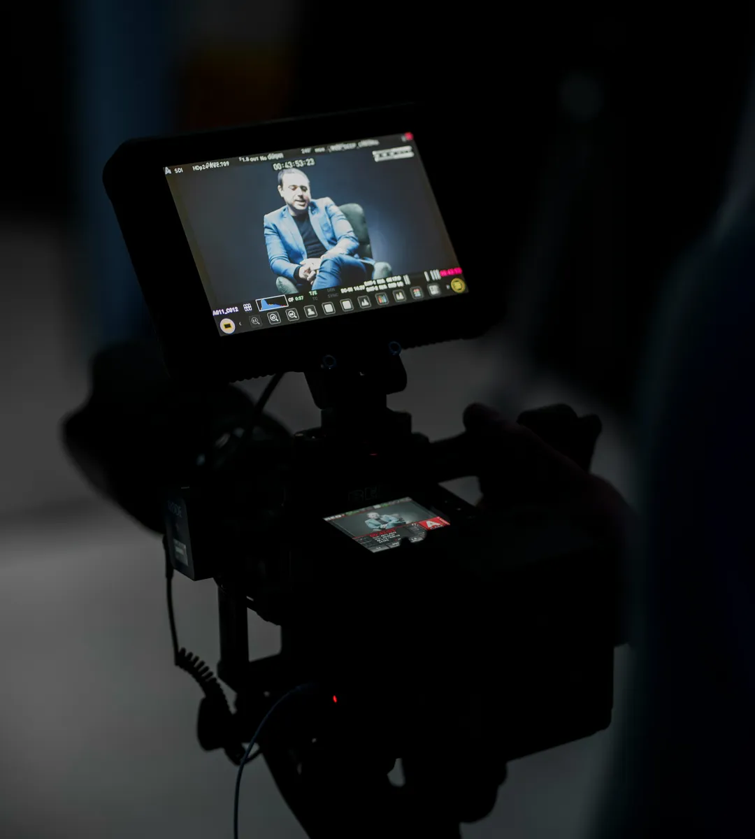 A camera monitor playing back a recorded interview in a darkened studio